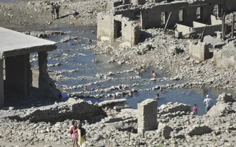 Ruinas de las termas de Yesa, con gente bañándose en las piscinas naturales formadas entre los escombros.