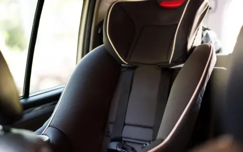 Silla de coche infantil, con cinturón de seguridad y detalles en blanco. La etiqueta indica ece r44/04 vigencia, asegurando su conformidad.