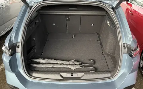 Maletero abierto de un Peugeot 308 SW con dos paraguas negros. Las medidas del maletero son amplias para equipaje.