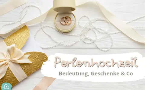 Hochzeitstags-Deko mit Ringen, Perlen und goldenem Umschlag. Die Perlenhochzeit Bedeutung wird hier gefeiert.