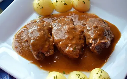 Carrilleras al vino tinto, tiernas y jugosas, bañadas en una rica salsa, acompañadas de patatas cocidas.