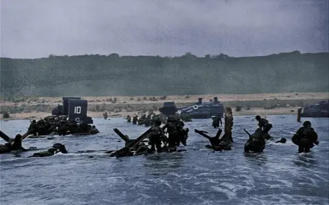 Soldati avanzano nell'acqua durante lo sbarco in Normandia. Un fotografo immortalò questo momento storico.