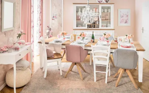 Ein Esstisch im Cottagecore-Stil, gedeckt mit Blumen und rosafarbenen Akzenten. Ein Kronleuchter hängt über dem Tisch.