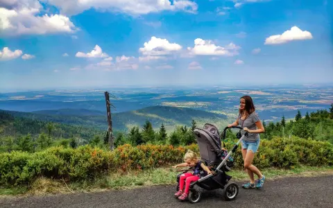 Mama z córką na spacerze, gdzie w góry z wózkiem. Piękny widok na dolinę i chmury.