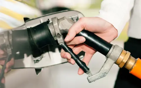Dłoń trzymająca pistolet do tankowania, gotowa do nalania gazu do diesla.