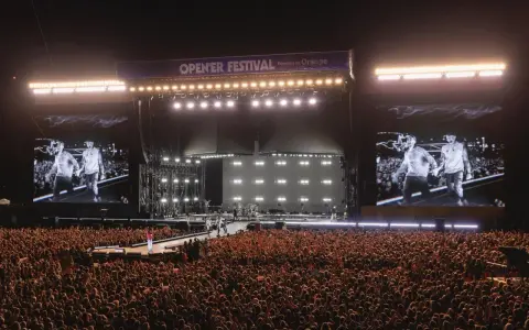 Ogromny tłum na Opener Festival, **ile ludzi**! Na scenie artyści, a na telebimach ich wizerunki.