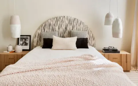 Camera da letto con testiera a semicerchio, cuscini decorativi e coperta rosa. Lampade a sospensione e comodini in legno completano l'arredamento, creando camere aesthetic.