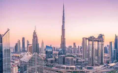 Dubaj o zachodzie słońca, z dominującym Burdż Chalifa, najwyższym budynkiem świata, otoczonym nowoczesnymi wieżowcami i autostradami.