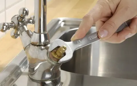 Hand repariert tropfenden wasserhahn mit einem Schraubenschlüssel.