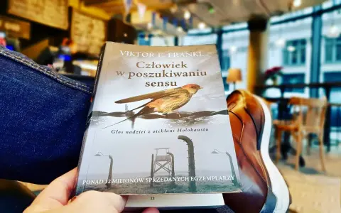 Osoba czyta "Człowiek w poszukiwaniu sensu" Viktora Frankla, szukając nadziei i znaczenia w trudnych czasach.