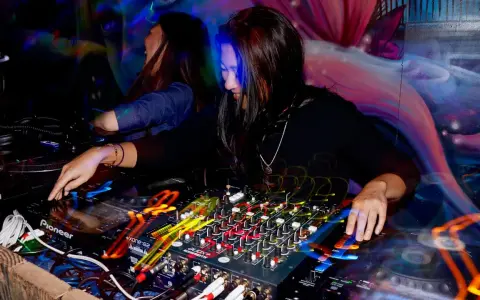 DJka miksuje energetyczne rytmy afro house w klubowej atmosferze. Kolorowe światła i dynamiczna muzyka tworzą niepowtarzalny klimat.