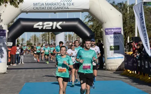 Corredores cruzan la meta de la distancia media maratón en Gandía.
