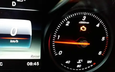 Gelbe motorkontrollleuchte leuchtet auf dem Armaturenbrett. Der Tachometer zeigt 0 km/h.