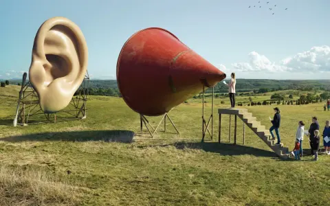 A surreal landscape by Erik Johansson photography. A giant ear stands next to a red megaphone, with people climbing stairs towards it.