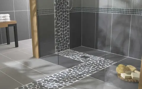 Carrelage moderne avec un chemin de galets sur le receveur de douche, créant une ambiance zen.