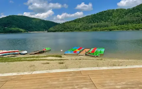 Kolorowe rowerki wodne i kajaki czekają na plaży nad górskim jeziorem.