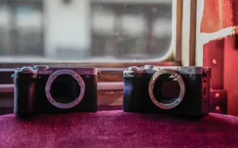 Dwa aparaty Sony Alpha, jeden a7c i drugi a7CR, leżą obok siebie na aksamitnym materiale.