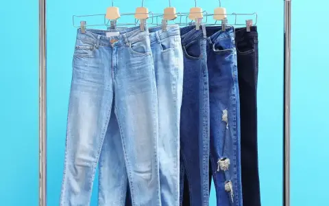 Różne modele jeansów na wieszakach. Czy rozmiar 27 spodnie damskie to Twój idealny rozmiar?