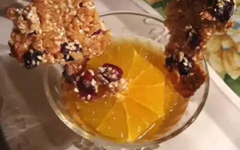 Délicieuse tuile de riz croustillante garnie de fruits secs, posée sur une tranche d'orange dans un verre.