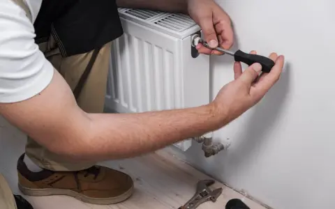 Man purga radiadores con un destornillador. Herramientas a su lado.