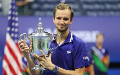 Daniil Medvedev, sonriendo, sostiene el trofeo del US Open, un logro que lo consolida entre los grandes de los medvedev grand slams.