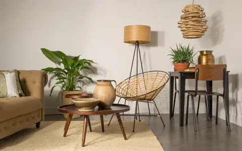 En mysig soffa, rottingfåtölj och ett runt bord med keramik skapar en inbjudande atmosfär. En golvlampa och en takkrona i rotting ger varmt ljus. En perfekt styla bokhylla visning.