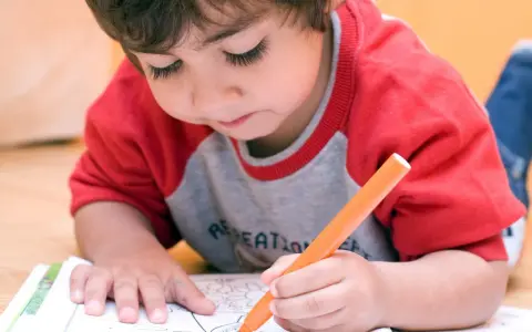 Bambino concentrato colora un disegno. A che età si capisce se un bambino è iperattivo? Osservare la sua attenzione e calma.