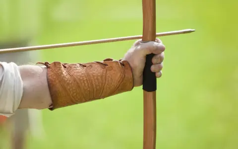 Mano con bracciale in cuoio, pronta a scoccare una freccia con l'arco, come un bellosguardo robin hood.