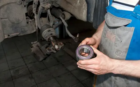 Mechanik trzyma nowe łożysko, przygotowując się do wymiany. Oto jak sprawdzić łożysko w kole przednim.
