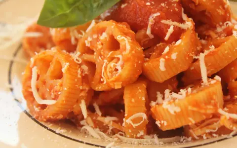 Pasta con ruote e rigatoni conditi con una ricca salsa di pomodoro Bimby, spolverata di parmigiano e guarnita con una foglia di basilico.