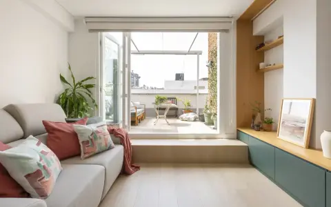 Ideas para decorar un salón rectangular: sofá gris, cojines coloridos, plantas y acceso a terraza.