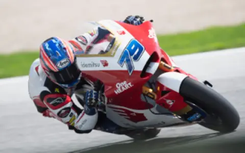 Piloto en plena curva durante una carrera de moto gp. La moto roja y blanca lleva el número 79.