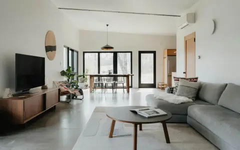 Salón moderno con sofá gris, mesa de centro y comedor. El color gris se combina con tonos madera y blanco, creando un ambiente sereno.
