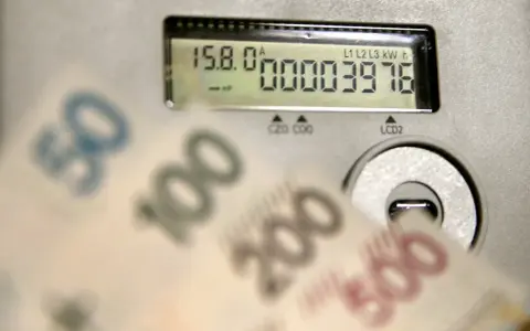 Opłata kogeneracyjna co to? Licznik energii i banknoty 50, 100, 200, 500 zł sugerują wysokie rachunki za prąd.