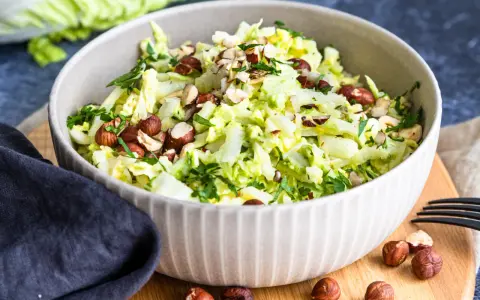 Frischer Chinakohlsalat mit gehackten Haselnüssen und Petersilie, serviert in einer Schüssel.