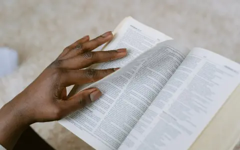 Dłoń przewracająca strony Biblii, szukająca pocieszenia w Psalmie 27.