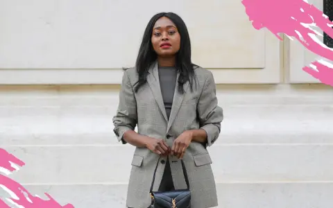 Eine Frau im karierten Blazer und schwarzer Tasche verkörpert einen schicken, lässigen Business-Look für Damen.