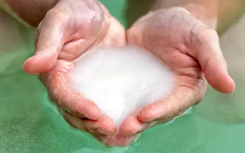 Hands cupped, holding foamy water, ready for a relaxing magnesium foot soak.