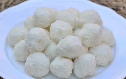 Un mucchio di dolci palline di cocco su un piatto bianco, perfette per una pausa golosa.