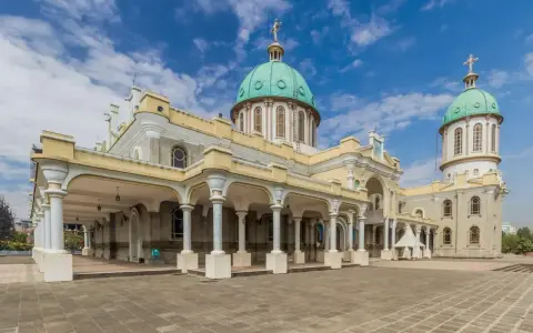 Katedra Świętej Trójcy w Addis Abebie, z zielonymi kopułami i kolumnowym portykiem, pod błękitnym niebem.