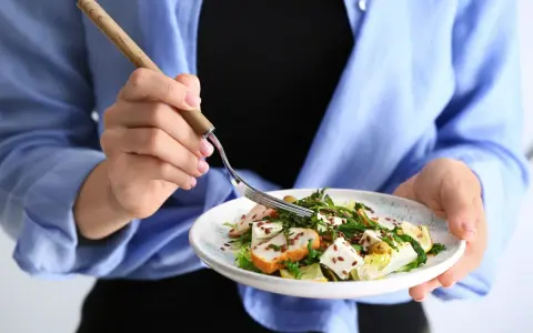 Kobieta je sałatkę z kurczakiem i serem feta, idealną na dietę 1200 kcal.