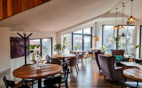 Przytulna restauracja w Bukowinie Tatrzańskiej z widokiem na góry. Drewniane stoły, wygodne fotele i stylowe oświetlenie tworzą ciepłą atmosferę.