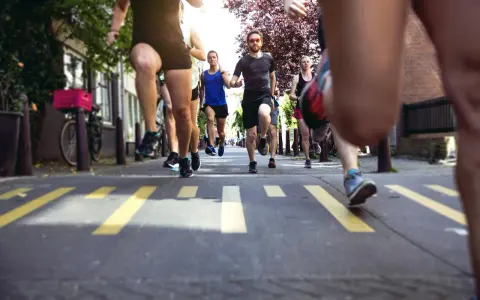 En grupp löpare kämpar sig fram på asfalten, redo att springa halvmaraton. Gula linjer på vägen markerar banan.