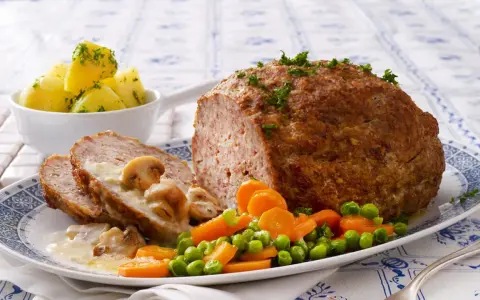 Herzhaftes Hackbraten-Mittagessen nach Omas Rezepten, serviert mit Salzkartoffeln, Pilzrahmsoße und Gemüse.