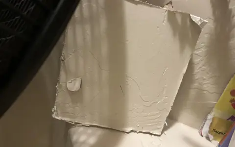 Uszkodzony fragment karton gipsu, który wymaga naprawy. Pokazuje, jak załatać dziurę w karton gipsie, aby ściana wyglądała jak nowa.