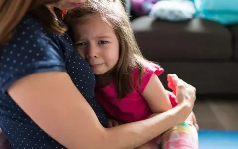 Mała dziewczynka płacze, wtulona w mamę. To właśnie parenting – trudne chwile i bezwarunkowa miłość.
