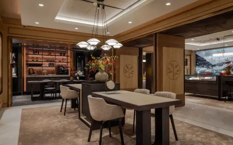 Interno di un elegante **progetto gioielleria** con tavoli in legno, sedie imbottite, un'area bar e vetrine espositive.