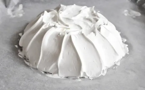 Idealna beza pavlova, która zawsze wychodzi, z puszystą pianką uformowaną na papierze do pieczenia.