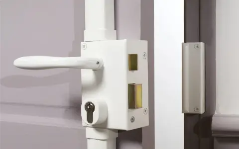 Poignée et serrure blanche avec barillet visible, prête à être verrouillée. Une clé de chaque côté assure la sécurité.