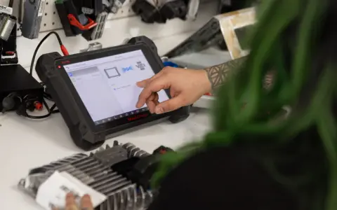 Mechanic uses a diagnostic tablet to connect to a car's ecm.